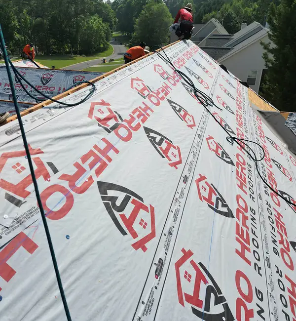 Hero Roofing branded synthetic underlayment being installed on a roof
